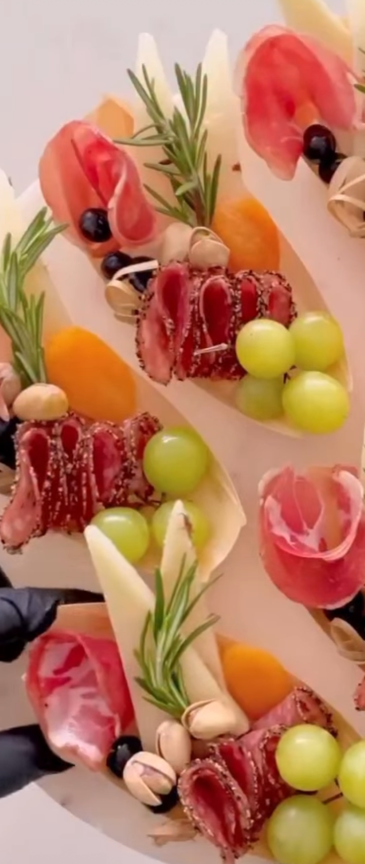 Wooden boats arranged with grapes, cheese, savory bites, and rosemary.