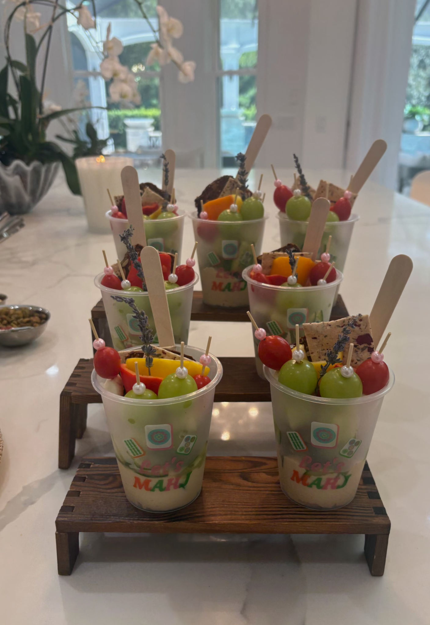 Mahjong themed cups filled with colorful small bites and displayed on wooden risers
