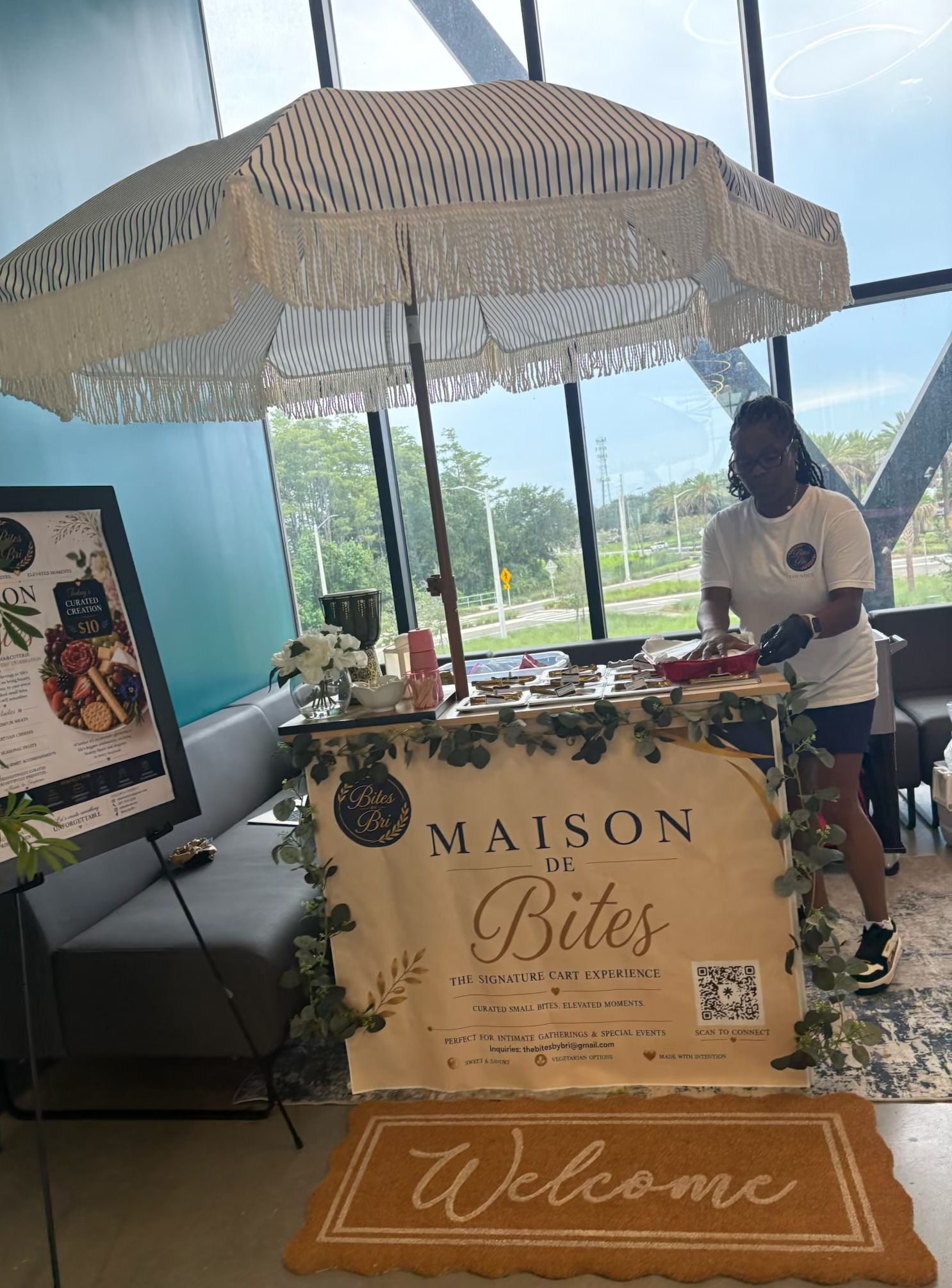 Bri preparing selections at the Maison de Bites cart beneath a fringed umbrella